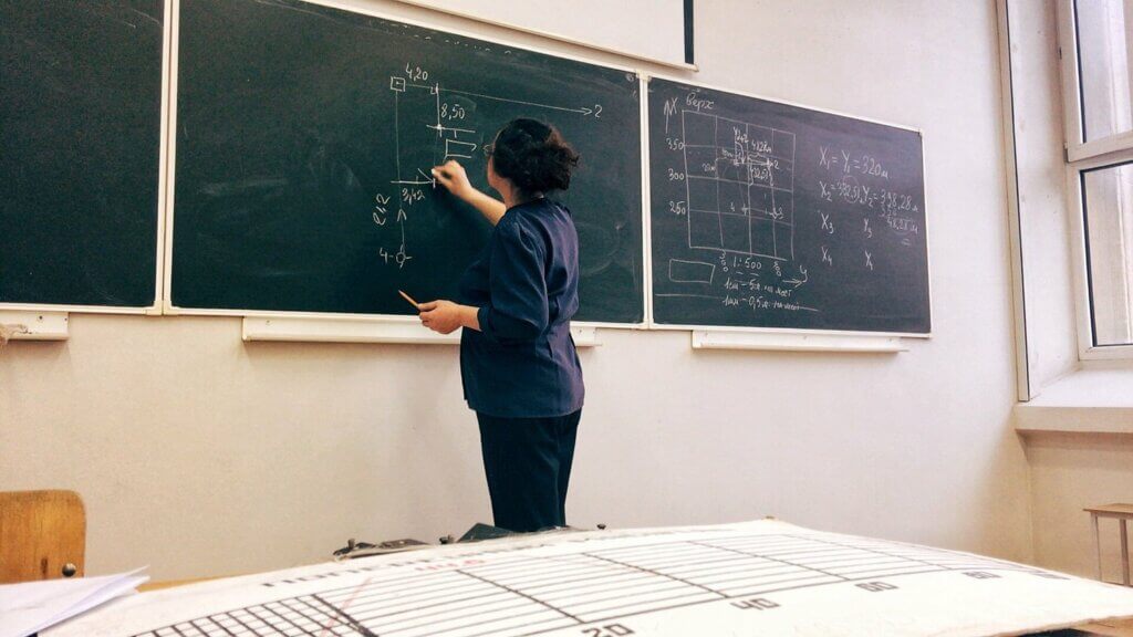 Teacher at a chalkboard working on a problem
