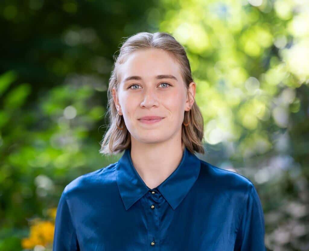EcoNW woman outdoors in nature, smiling confidently.