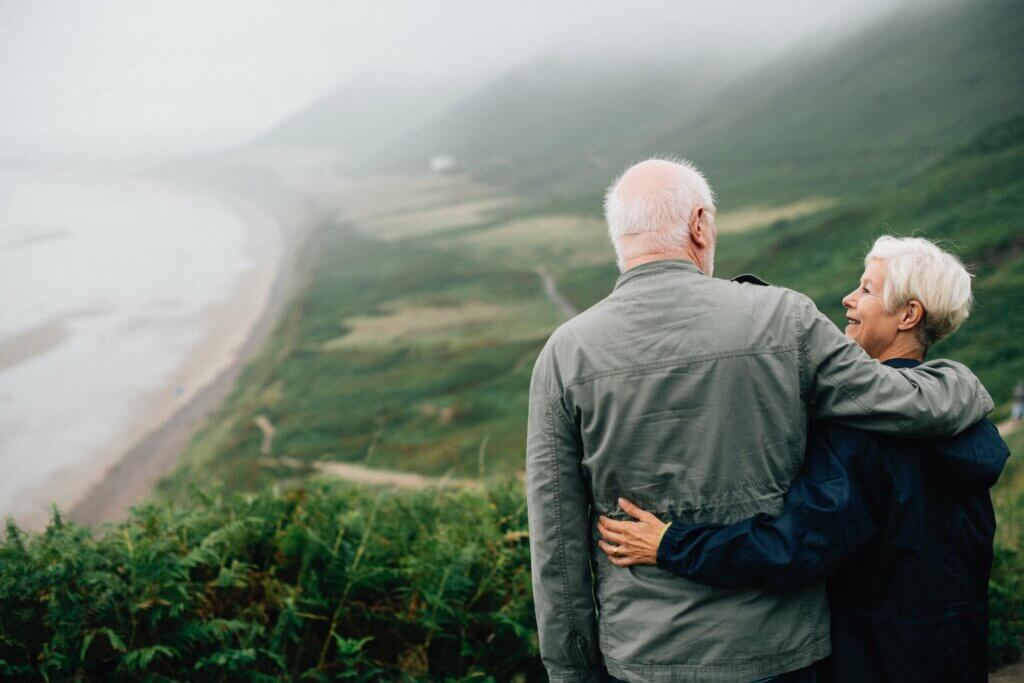 Older couple hugging and looking over coastal view